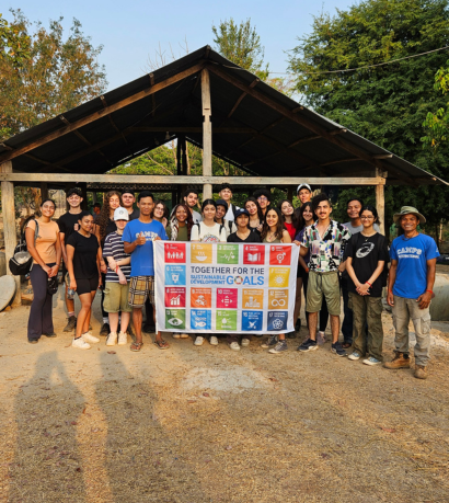 Student travellers on a Cambodia School Expedition with Camps International holding up SDG Flag in front of Water Pot project
