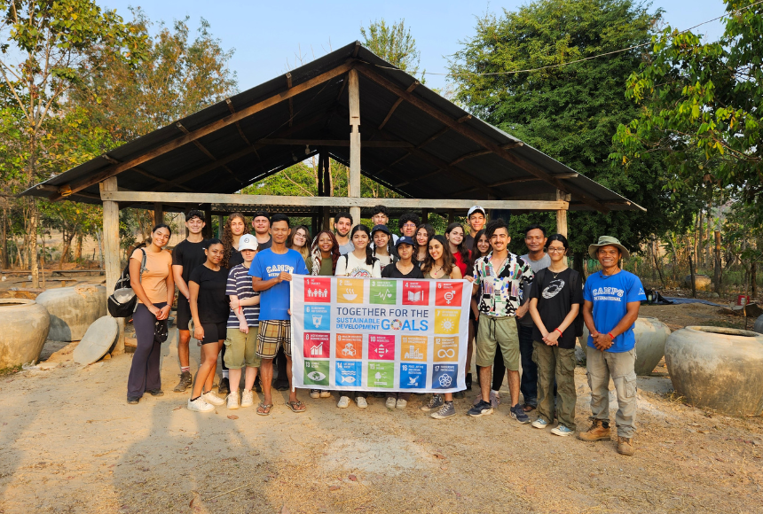 Student travellers on a Cambodia School Expedition with Camps International holding up SDG Flag in front of Water Pot project