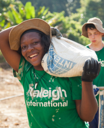 Raleigh Venturer, wearing a green Raleigh T-shirt and caring supplies as they make their way to project location.