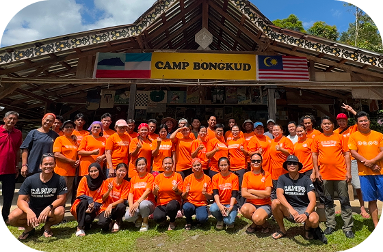 Meet our people behind the Impact Travel Group: Photo of team in Bongkud Borneo in orange t-shirts