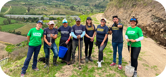 Meet our people behind the Impact Travel Group: Ecuador team in green and blue t-shirts with spades and buckets