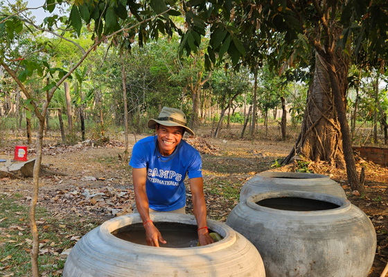 Picture of Han Project Manager from the local community next to two water pots